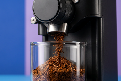 Coffee grounds dispensing from silver outlet into transparent cup