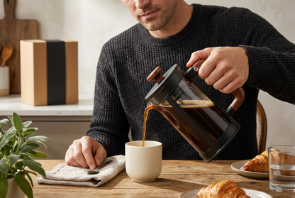 Man pouring French press coffee at breakfast
